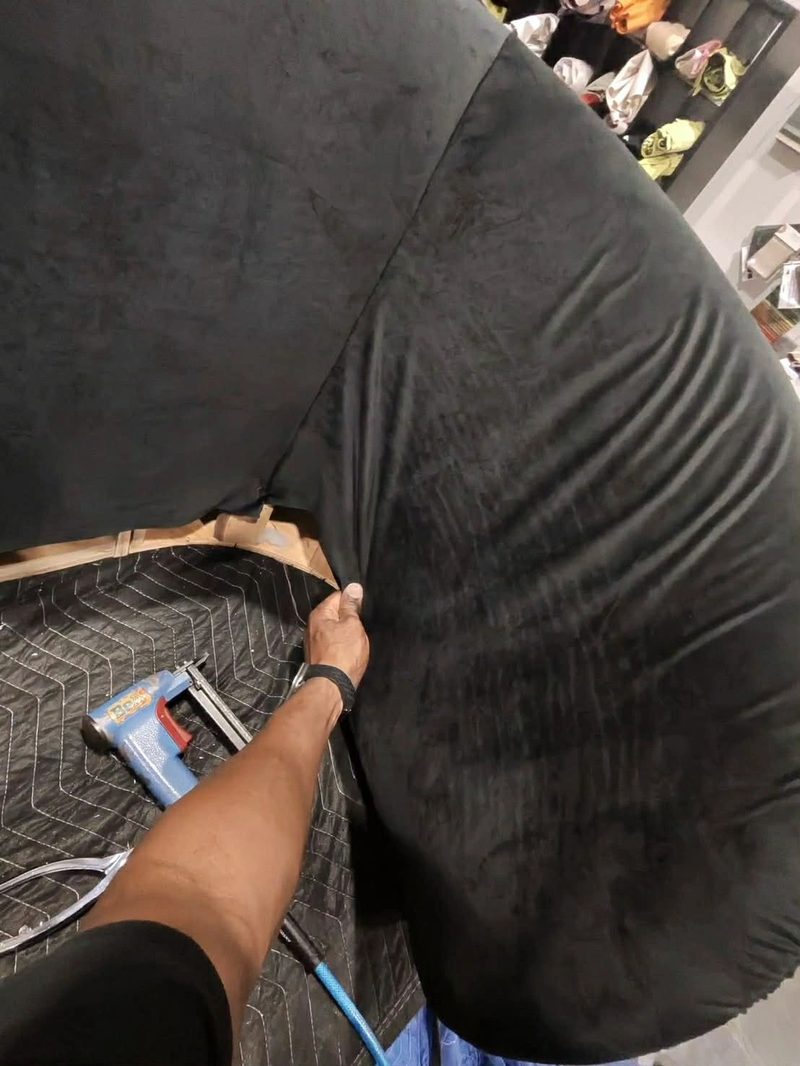 Stapling black velvet onto a curved furniture frame